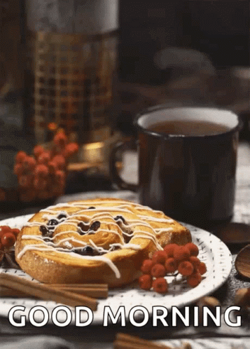 A Cinnamon Roll On A Plate Next To A Cup Of Tea With The Words Good Morning Written Below It GIF