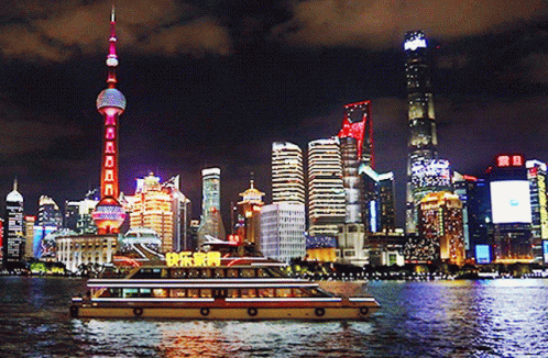 A City Skyline At Night With A Boat In The Foreground That Says ' Happy New Year ' On It GIF