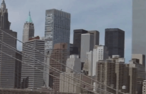 A City Skyline With A Bridge In The Foreground And One Of The Buildings Has The Word Brooklyn On The Top Of It GIF