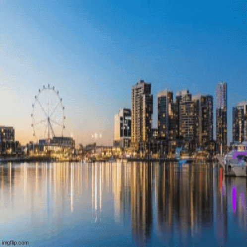 A City Skyline With A Ferris Wheel In The Foreground And A Body Of Water In The Foreground GIF
