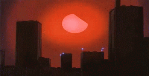 A City Skyline With A Large Red Sun Behind It GIF