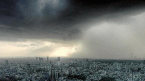 A City Under A Cloudy Sky With A Few Buildings In The Foreground GIF