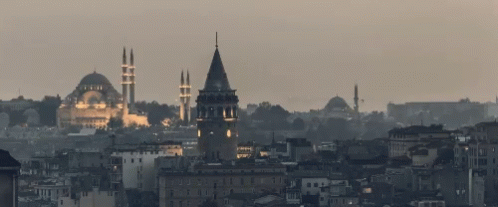 A Cityscape With A Clock Tower And A Mosque In The Distance GIF