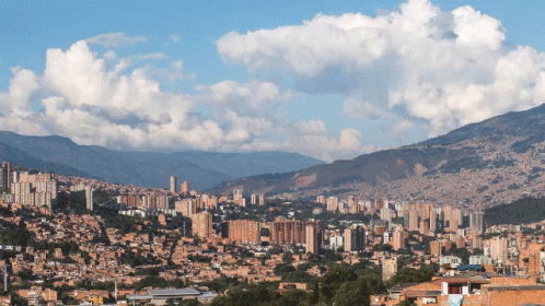 A Cityscape With Mountains In The Background And A Blue Sky GIF