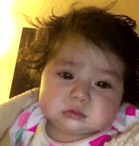 A Close Up Of A Baby 'S Face With A Blanket Around Her GIF