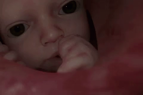 A Close Up Of A Baby 'S Face With A Person 'S Finger In It GIF