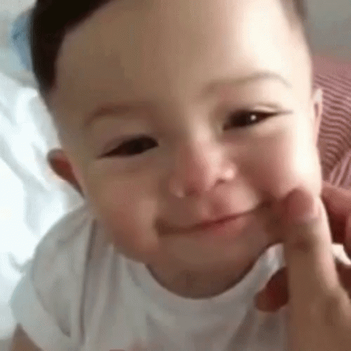 A Close Up Of A Baby 'S Face With A Person 'S Hand On It . GIF