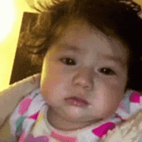 A Close Up Of A Baby 'S Face With A Pink And White Polka Dot Shirt On . GIF