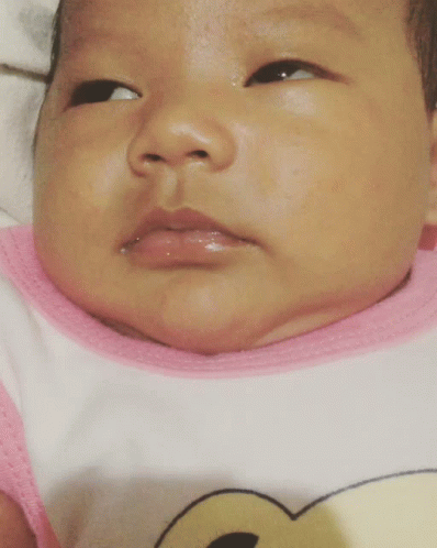 A Close Up Of A Baby 'S Face With A Pink And White Shirt On GIF