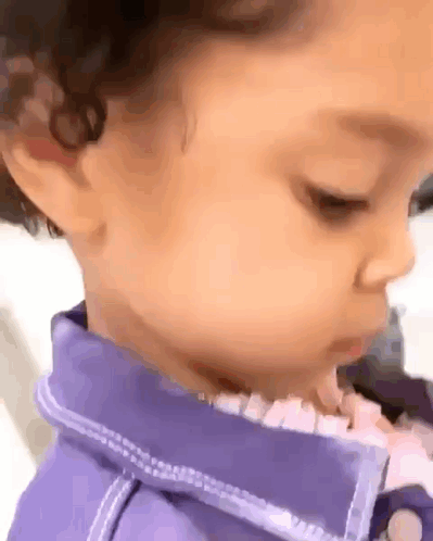 A Close Up Of A Baby 'S Face With A Purple Shirt On . GIF
