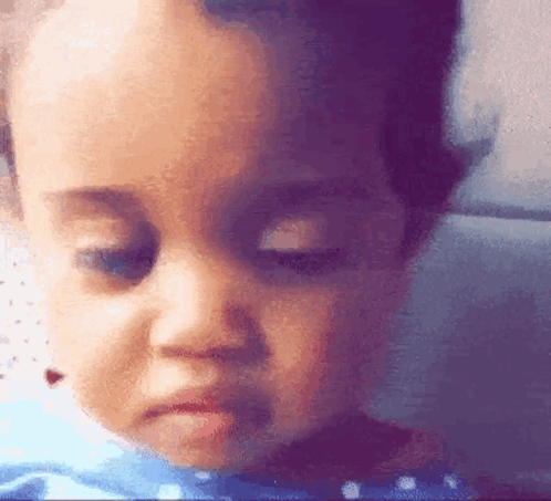 A Close Up Of A Baby 'S Face With A Sad Look On His Face GIF