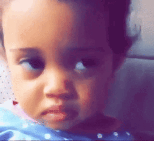 A Close Up Of A Baby 'S Face With A Sad Look On It . GIF