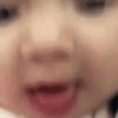 A Close Up Of A Baby 'S Face With Its Mouth Open And Teeth Visible . GIF