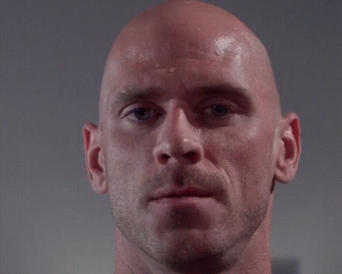 a close up of a bald man 's face with a hand touching his forehead