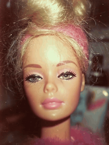 A Close Up Of A Barbie Doll With A Pink Headband On Her Head GIF
