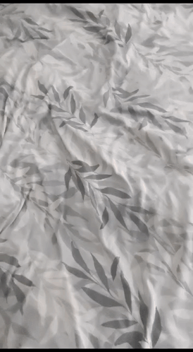 A Close Up Of A Bedspread With A Leafy Pattern GIF