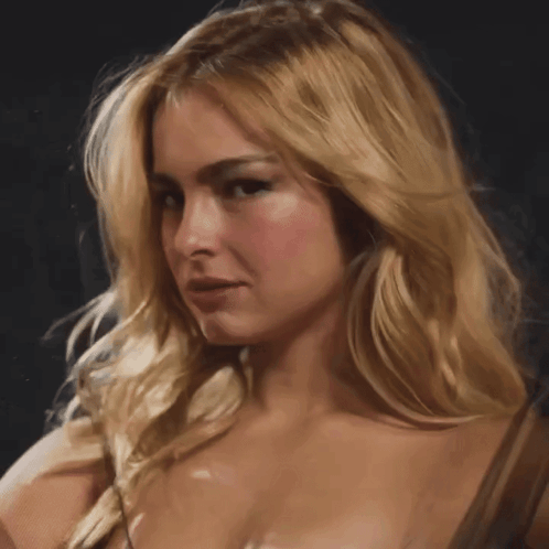 A Close Up Of A Blonde Woman 'S Face With A Dark Background GIF