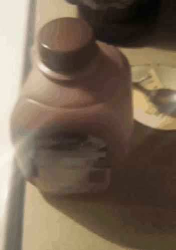 A Close Up Of A Bottle Of Milk With A Spoon In It GIF