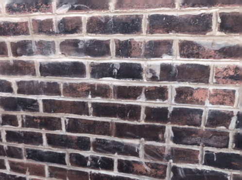A Close Up Of A Brick Wall With A Few White Bricks GIF