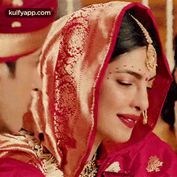 A Close Up Of A Bride Wearing A Red And Gold Dress And Veil . GIF