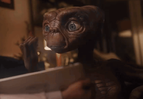 A Close Up Of A Brown Alien With Blue Eyes Looking At The Camera GIF