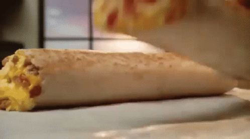 A Close Up Of A Burrito On A Table Being Eaten . GIF