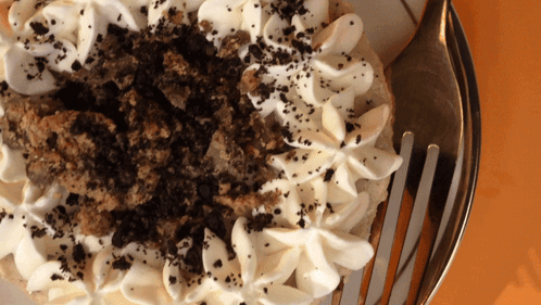 A Close Up Of A Cake With Whipped Cream And Crumbs On Top GIF