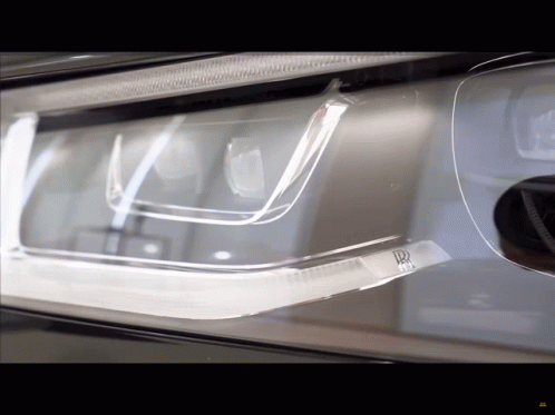 A Close Up Of A Car Headlight With A R On It GIF