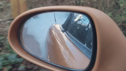 A Close Up Of A Car Rear View Mirror With A Reflection Of A Car GIF