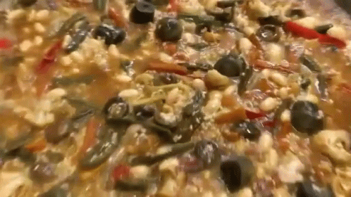 A Close Up Of A Casserole Dish With Beans , Olives , Peppers And Other Vegetables . GIF