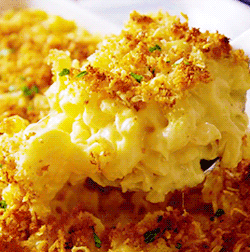 A Close Up Of A Casserole Dish With Macaroni And Cheese On A Spoon GIF