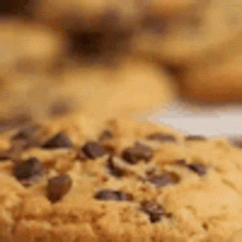A Close Up Of A Chocolate Chip Cookie On A Plate With Other Cookies . GIF