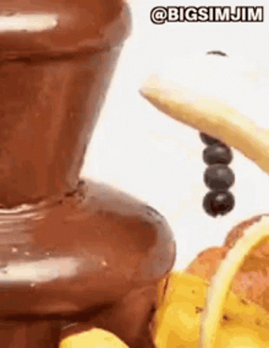 A Close Up Of A Chocolate Fountain With Bananas And Berries . GIF