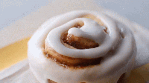 A Close Up Of A Cinnamon Roll With Icing GIF