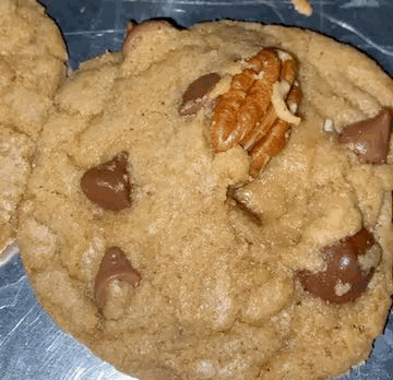 A Close Up Of A Cookie With Chocolate Chips And Pecans On It GIF