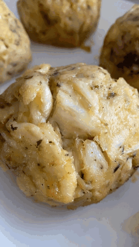 A Close Up Of A Crab Cakes On A White Plate GIF