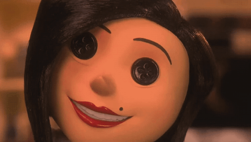 A Close Up Of A Doll 'S Face With Buttons In Her Eyes GIF