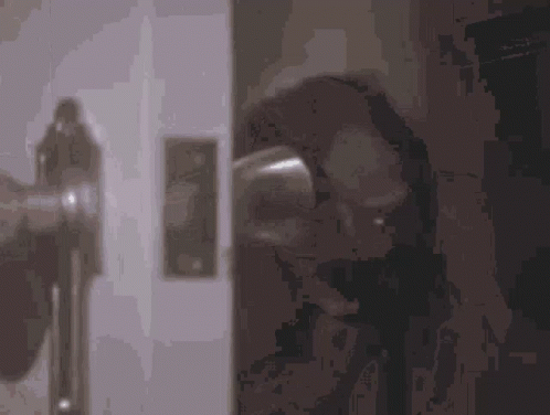 a close up of a door handle with a reflection of a person behind it .