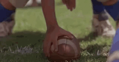 A Close Up Of A Football Being Kicked By A Player On A Field . GIF