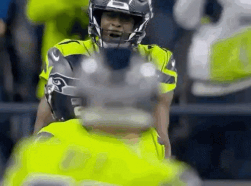 A Close Up Of A Football Player Wearing A Helmet And Holding A Football . GIF
