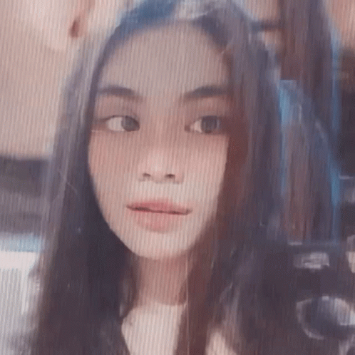 A Close Up Of A Girl 'S Face With Long Hair And A Striped Background . GIF