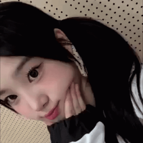 A Close Up Of A Girl With Her Hand On Her Face . GIF