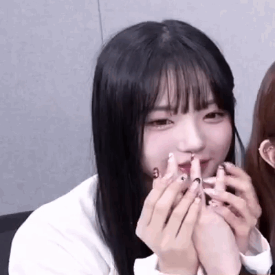 A Close Up Of A Girl With Long Black Hair Holding Her Hands To Her Face . GIF