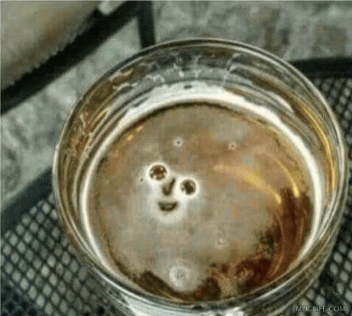 A Close Up Of A Glass Of Beer With A Smiley Face In It GIF