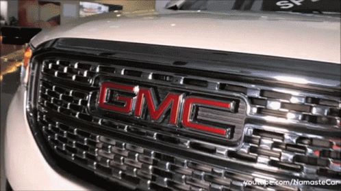 A Close Up Of A Gmc Logo On The Front Of A White Car GIF