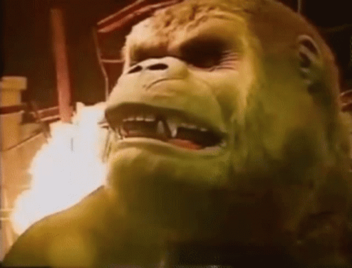 A Close Up Of A Gorilla 'S Face With Fire Coming Out Of It 'S Mouth . GIF