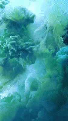 A Close Up Of A Green And Blue Smoke Coming Out Of The Water GIF