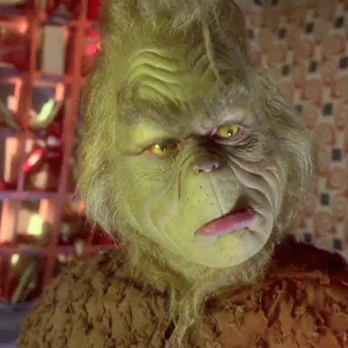 A Close Up Of A Grinch 'S Face With His Tongue Sticking Out . GIF