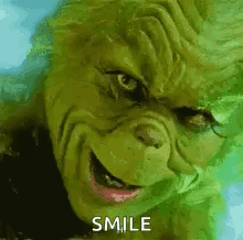 A Close Up Of A Grinch 'S Face With The Words `` Smile '' Written On It . GIF