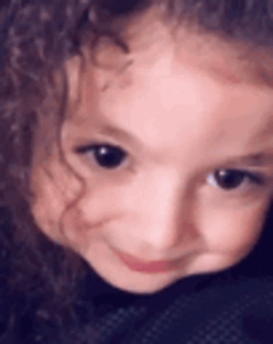 A Close Up Of A Little Girl 'S Face With Curly Hair . GIF